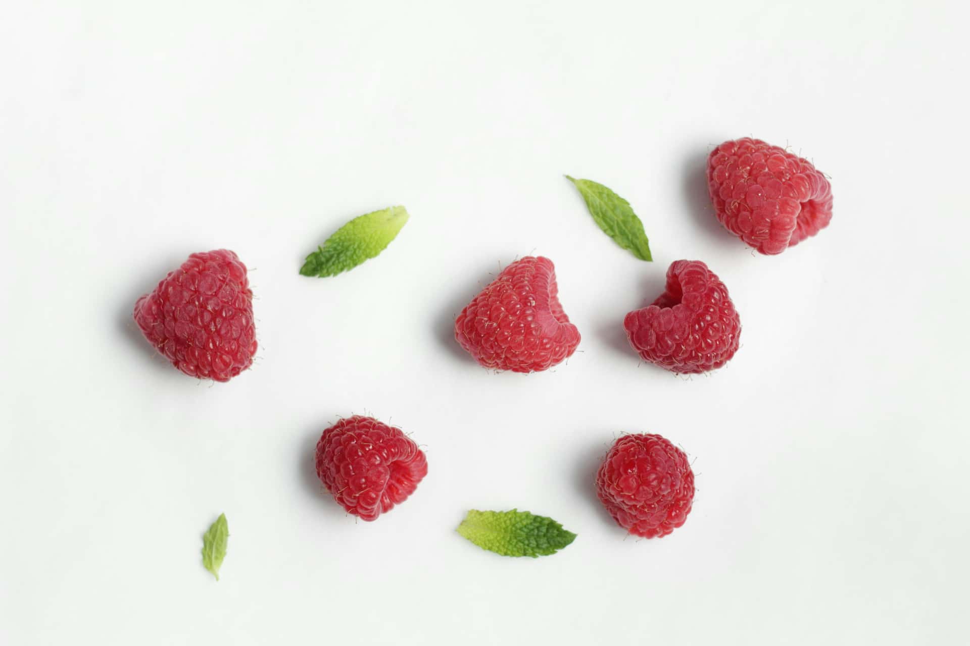 Fresh raspberries scattered on a white surface