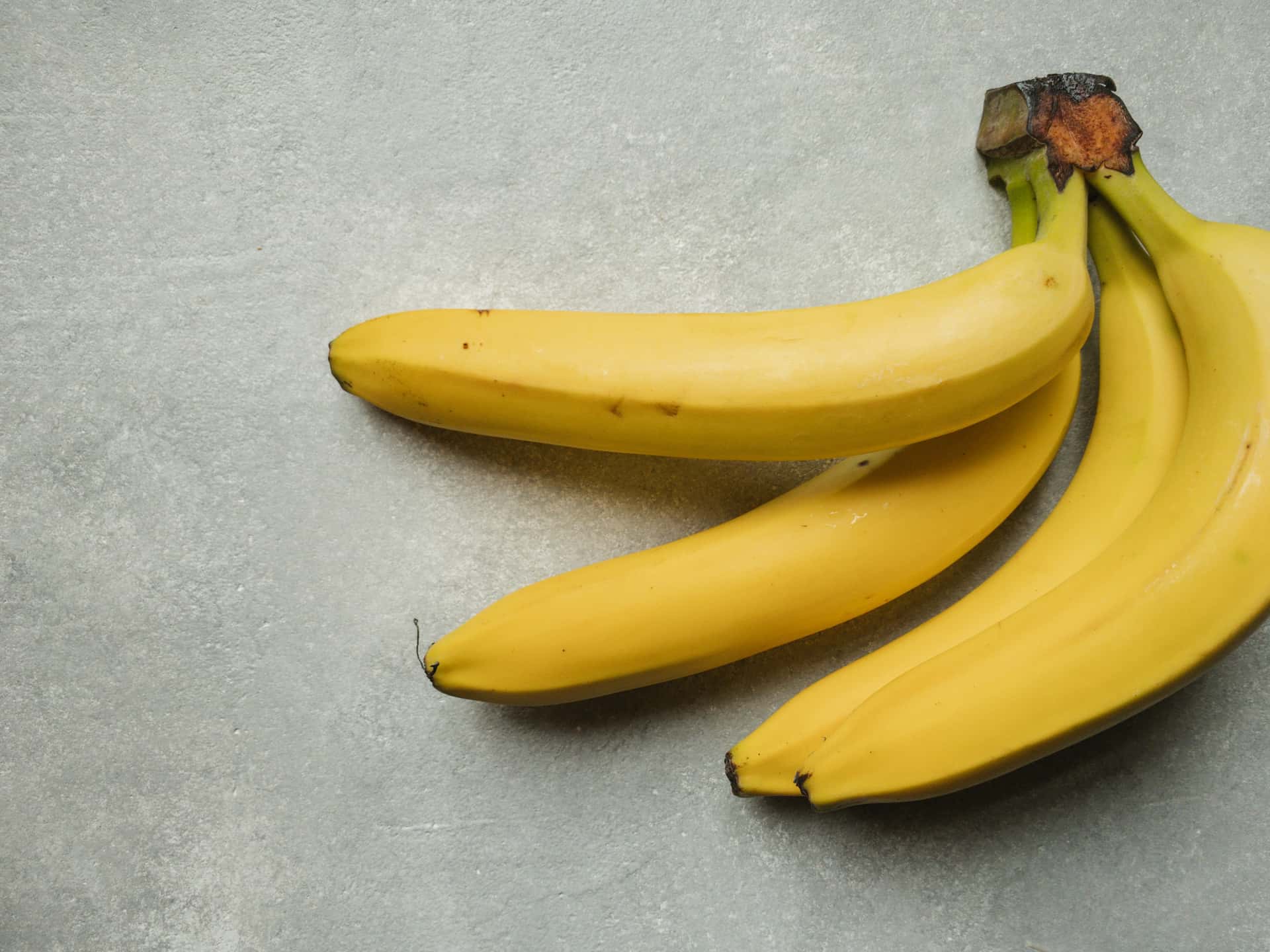 Ripe yellow bananas on a grey table