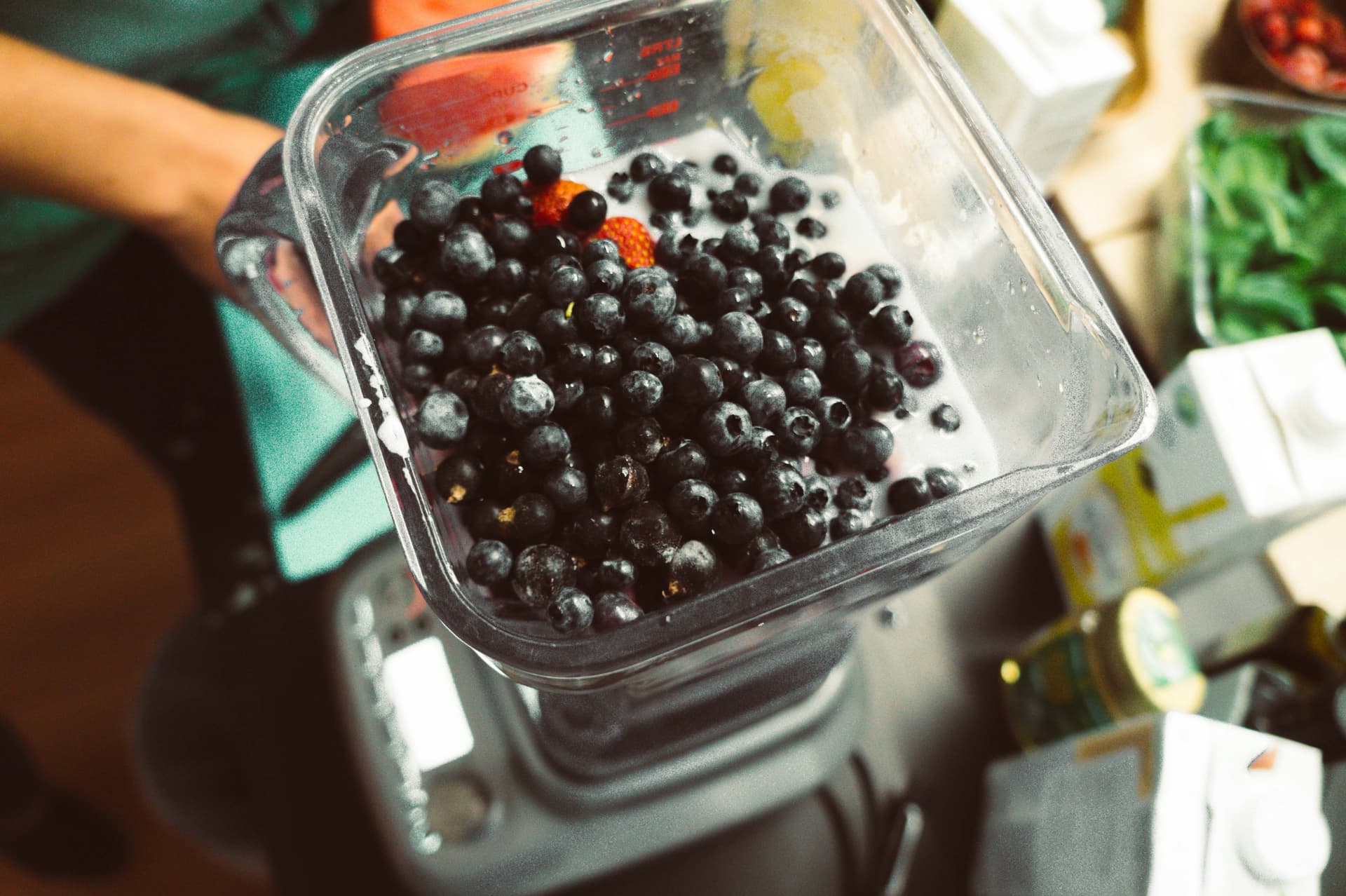 Frozen blueberries in a glass blender jug on a kitchen counter