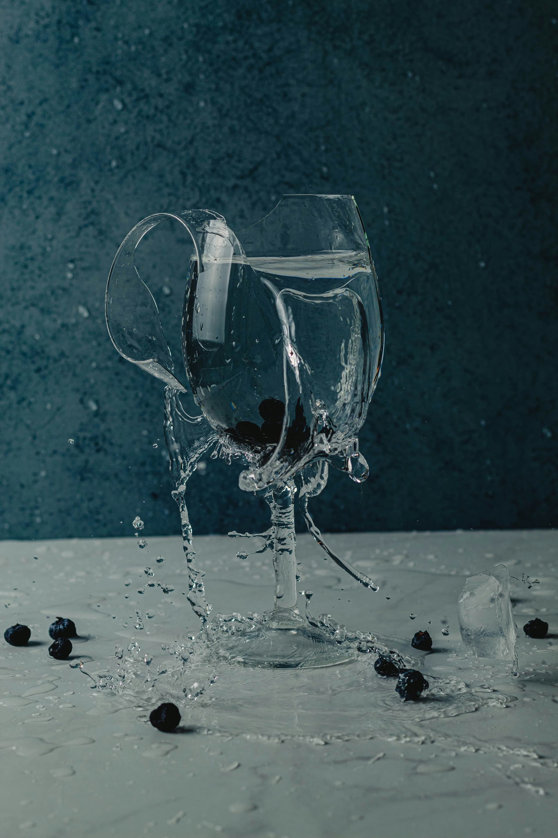 Blueberries splashing into a glass of water against a dark background